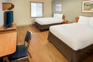 杰汉奈WoodSpring Suites Columbus NE I-270 Airport的酒店客房设有两张床、一张桌子和一台电视。