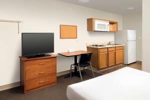 邓肯WoodSpring Suites Spartanburg Duncan的酒店客房设有一张书桌、一台电视和一间厨房