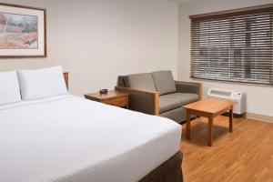 基林WoodSpring Suites Killeen的卧室配有床、椅子和窗户。