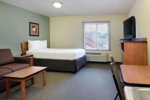 里士满WoodSpring Suites Richmond West I-64的酒店客房配有床、沙发和电视。