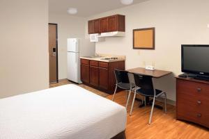 圣安东尼奥WoodSpring Suites San Antonio Fort Sam的酒店客房设有一张床和一间带桌子及电视的厨房