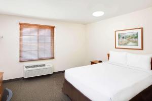 休斯顿WoodSpring Suites Houston Willowbrook的卧室设有一张白色大床和一扇窗户。