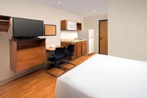 圣安吉洛WoodSpring Suites San Angelo的一间卧室配有一张床和一张书桌及电视
