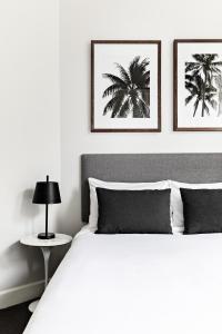 悉尼St Marks Randwick的卧室配有一张白色床,墙上挂有两张照片