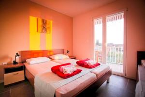 波达卡Apartments Kalaba - Dalma II的一间卧室设有两张带红色床单的床和窗户。
