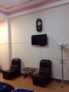大叻Hostel Khanh Hương 2的一间设有两把椅子和墙上一个时钟的房间