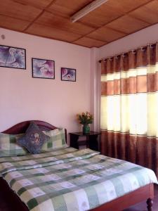 大叻Hostel Khanh Hương 2的一间卧室配有床和两个带窗帘的窗户