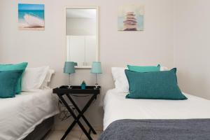 巴利托Ballito Luxury Apartment的一间卧室配有两张床和一张带镜子的桌子