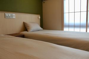 京都HIZ HOTEL Gion-Shirakawa的客房设有两张床和窗户。