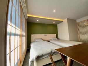 京都HIZ HOTEL Gion-Shirakawa的一间卧室设有两张床、一张桌子和一个窗口