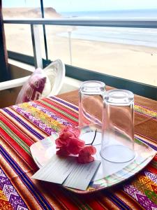奇卡马港Surf House Chicama的一张桌子,上面有两杯眼镜,盘子上放着鲜花