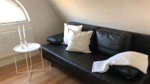 罗拉赫City Apartment的一张带白色枕头和桌子的黑色皮沙发