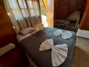坎波斯杜若尔当Villa Valentina chalés com lareira e churrasqueira的一间卧室配有带2条白色毛巾的床