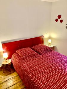 凯泽贝尔Gite "La Maison Jaune" à Kaysersberg avec garage的卧室内的一张红色的床,配有两盏灯