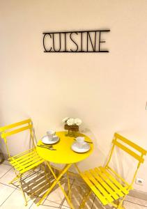 凯泽贝尔Gite "La Maison Jaune" à Kaysersberg avec garage的一张带两把椅子的黄色桌子和一个读菜的标牌