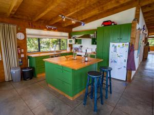 PakawauMohua - Pakawau Holiday Home的一个带绿色橱柜的厨房和一个带凳子的厨房岛