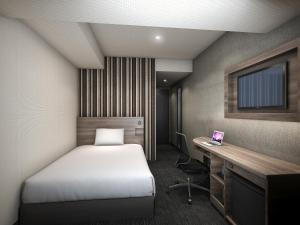 大阪Smile Hotel Shin-osaka的一间卧室配有一张床、一张书桌和一台笔记本电脑