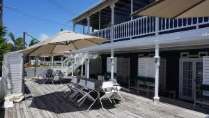 怀蒂昂格Nana Glads Beachfront Accommodation的木甲板配有桌子和遮阳伞