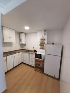 科马鲁加Apartamento a 300 mts de la playa, 25 minutos de Port Aventura y 50 de Barcelona的厨房配有白色橱柜和白色冰箱。