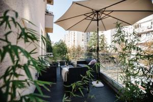 莫斯塔尔Big Tree Apartment & The Nest Apartment - free Parking的阳台的天井配有遮阳伞和家具。