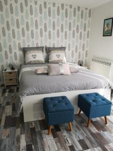 尚尼耶Chambre d’hôtes des tourterelles的一间卧室配有一张大床和两张蓝色凳子