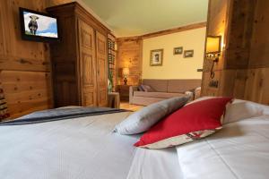 布吕松Laghetto Alpine Hotel & Restaurant的卧室配有一张床铺,墙上配有电视