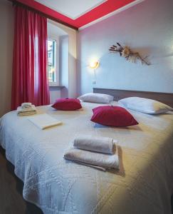 莫托文Guest House Nena的一张白色大床,配有红色枕头和毛巾