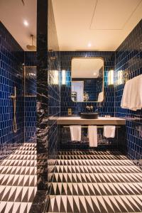科克The Dean Cork的浴室设有蓝色瓷砖墙壁、水槽和镜子