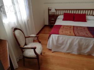 卢耶哥索摩查Hotel Rural Molino del Arriero的一间卧室配有一张带红色枕头的床和一把椅子