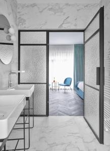 列日Amosa Liège City Centre Hotel的一间带浴缸和水槽的浴室以及一间卧室