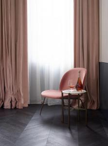 列日Amosa Liège City Centre Hotel的粉红色的椅子和一张带一瓶葡萄酒的桌子
