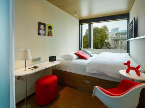 伦敦伦敦塔世民酒店的一间卧室设有床、窗户和红色椅子