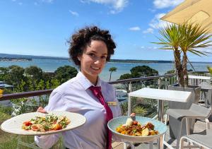 浦耳海峰酒店的阳台上拿着两盘食物的妇女