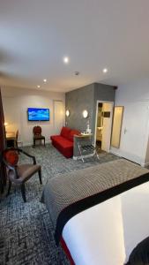 布尔日Logis - Le Christina的酒店客房,配有一张床和一张红色的沙发