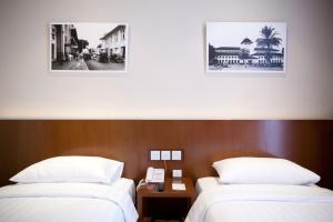 万隆万隆普莱姆公园酒店的两张位于酒店客房的床,墙上有两张照片