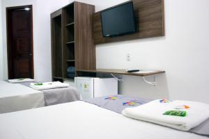 福塔莱萨Pousada Arco Iris Fortaleza的客房设有三张床和一台平面电视。