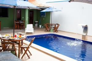 福塔莱萨Pousada Arco Iris Fortaleza的一个带桌椅和遮阳伞的游泳池