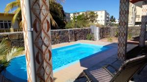 弗利康弗拉克3 bedrooms apartement at Les plaines Saint Pierre Flic en Flac 800 m away from the beach with shared pool enclosed garden and wifi的一座带椅子的游泳池,毗邻石墙