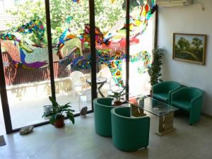 普列文Family Art Hotel Gallery的客房设有绿色椅子、桌子和窗户。