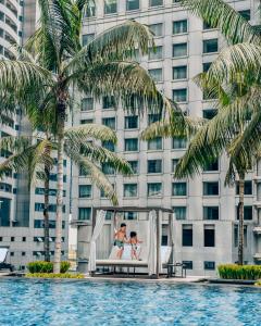 吉隆坡吉隆坡君悦酒店的在酒店的游泳池前穿着婚礼礼服的新娘和新郎