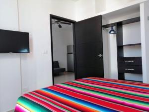 普拉亚卡门Condo Kiaraluna的一间卧室配有一张带彩色条纹毯子的床