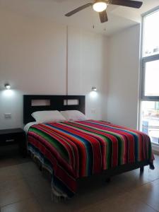普拉亚卡门Condo Kiaraluna的一间卧室配有一张带彩色毯子的床