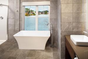 萨拉纳克莱克Saranac Waterfront Lodge的带浴缸、水槽和窗户的浴室