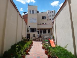 拉巴斯Rendezvous Hostal的建筑前方有盆栽植物的砖砌走道