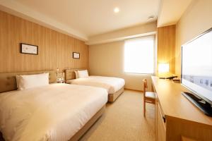 东京hotel MONday Haneda Airport的酒店客房设有两张床和一台平面电视。