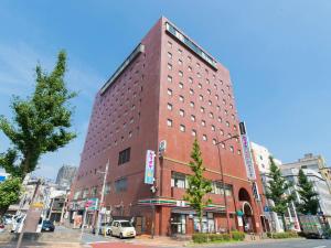 北九州Tabist Hotel Tetora Kitakyushu的城市街道上一座高大的红砖建筑