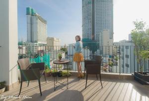 芽庄Mojzo Inn Boutique Hotel的站在一个享有城市美景的阳台上的女人