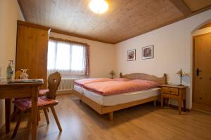GsteigHotel Bären的一间卧室配有一张床、一张书桌和一个窗户。