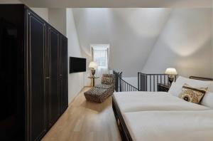 因斯布鲁克施沃泽阿德勒因斯布鲁克酒店的一间卧室配有一张床、一把椅子和电视