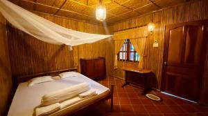 永隆mekong riverside homestay的一间卧室配有一张床、一张桌子和一个窗户。